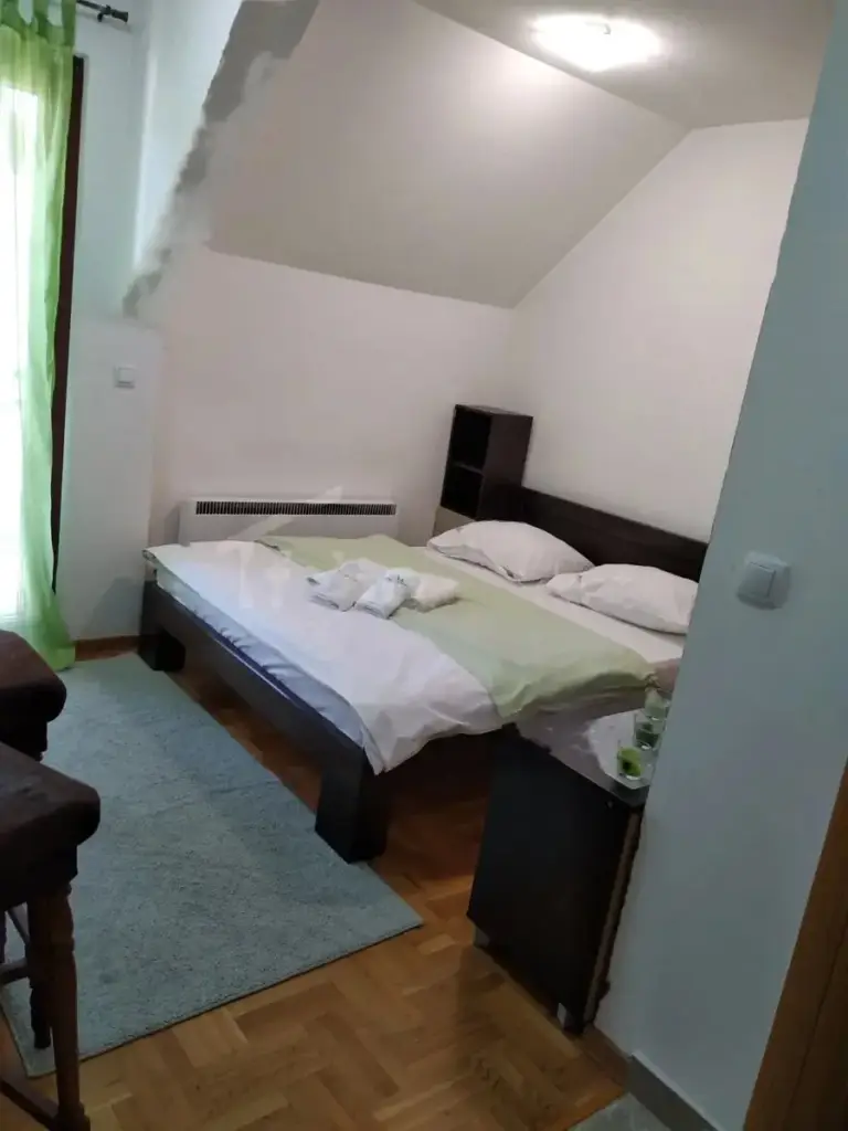Small bedroom with double bed, green curtains, and rug