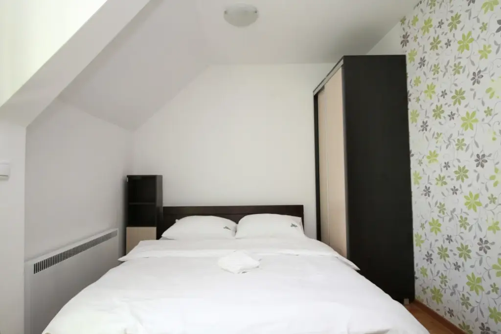 Small bedroom with white bed and wardrobe