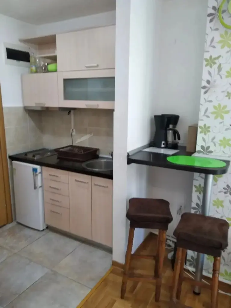 Small kitchen with cabinets, fridge, coffee maker, and stools