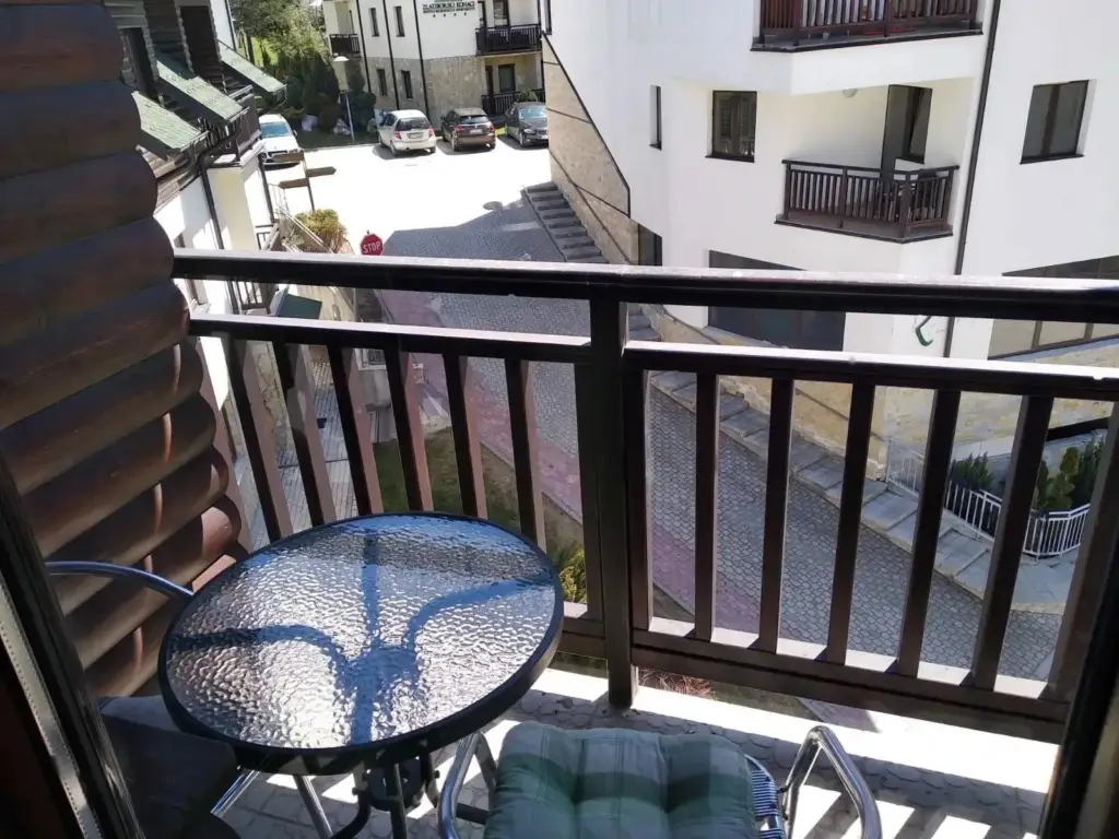 Balcony with glass table, chair, and street view