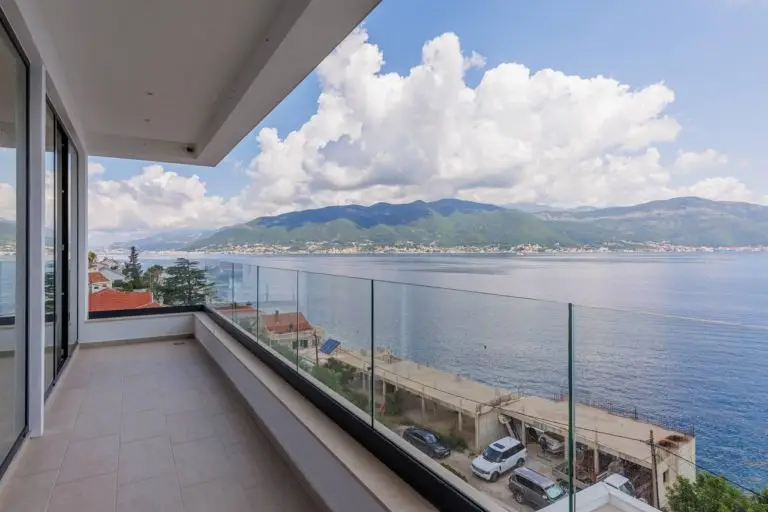 Balcony with glass railing overlooking a bay and mountains