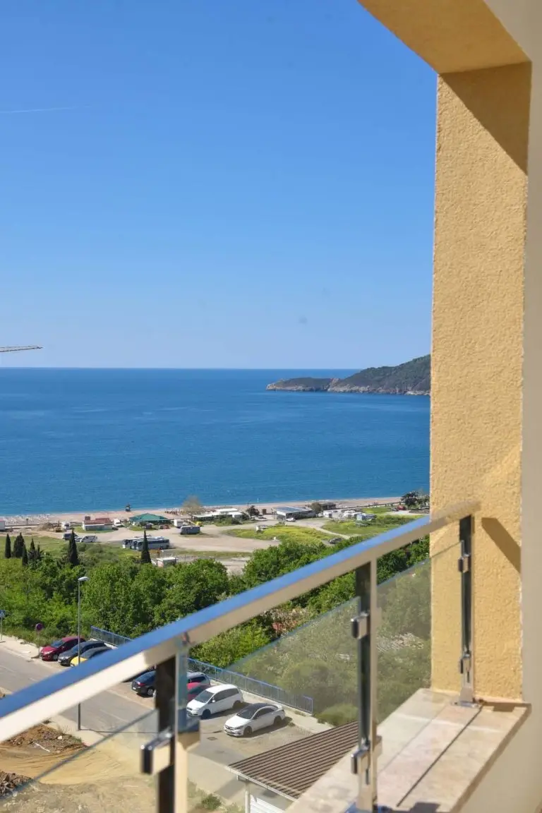 Balcony view of sea, beach, and parked cars