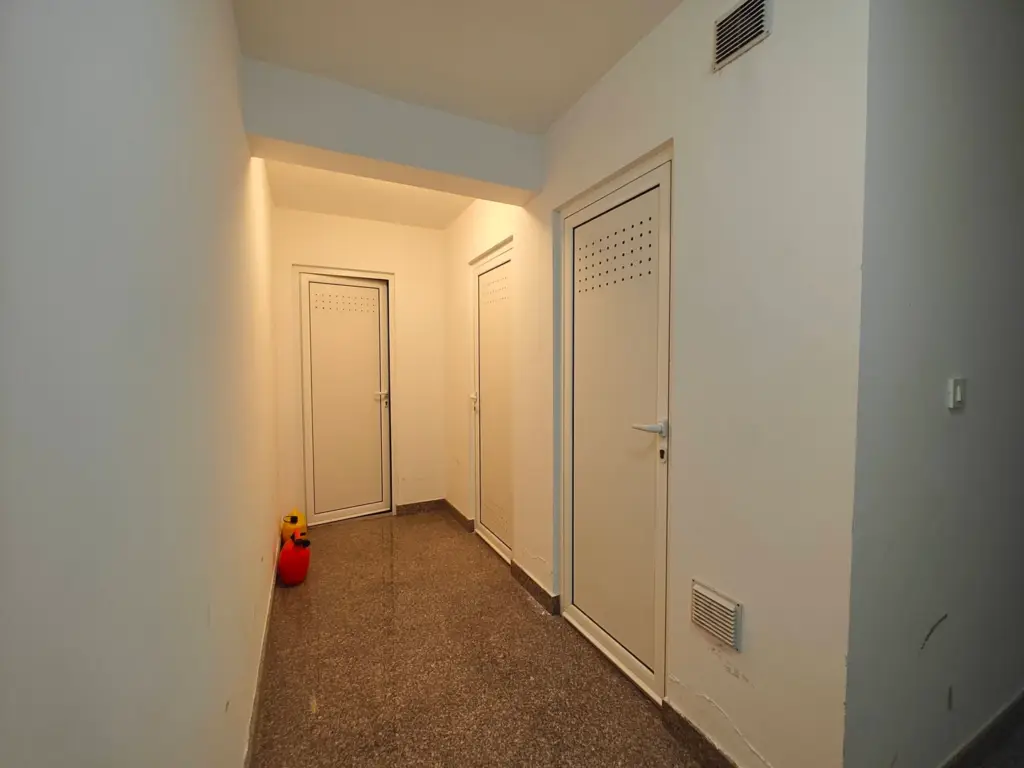 Narrow hallway with three white doors and a fire extinguisher
