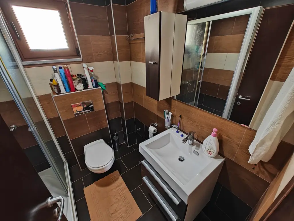 Small bathroom with shower, sink, toilet, and mirror cabinet