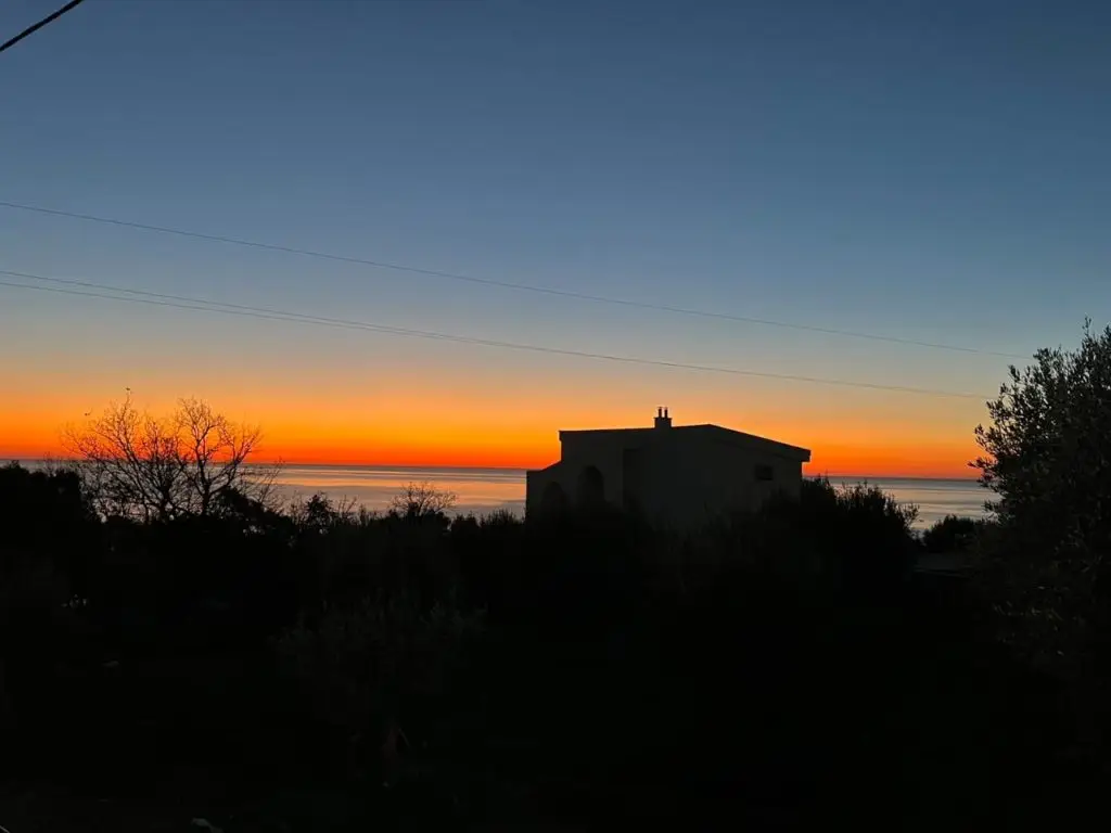 Silhouetted house overlooking the sea at sunset