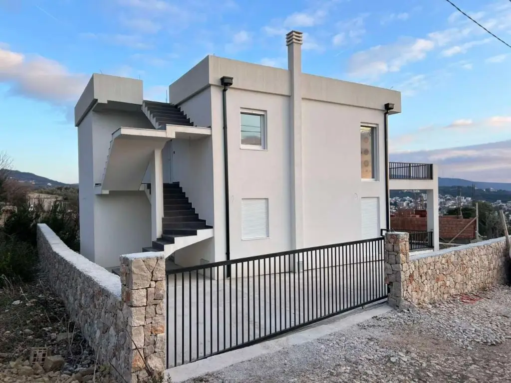 Modern white two-story house with external stairs and black gate