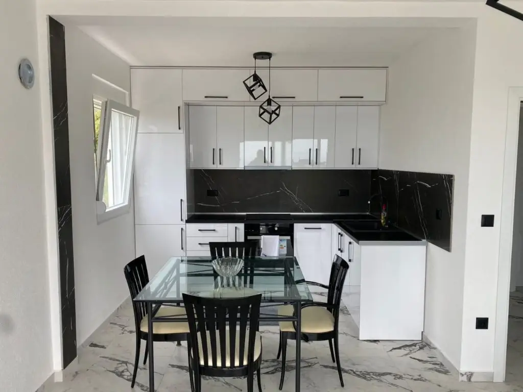 Modern black-and-white kitchen with glass dining table and four chairs