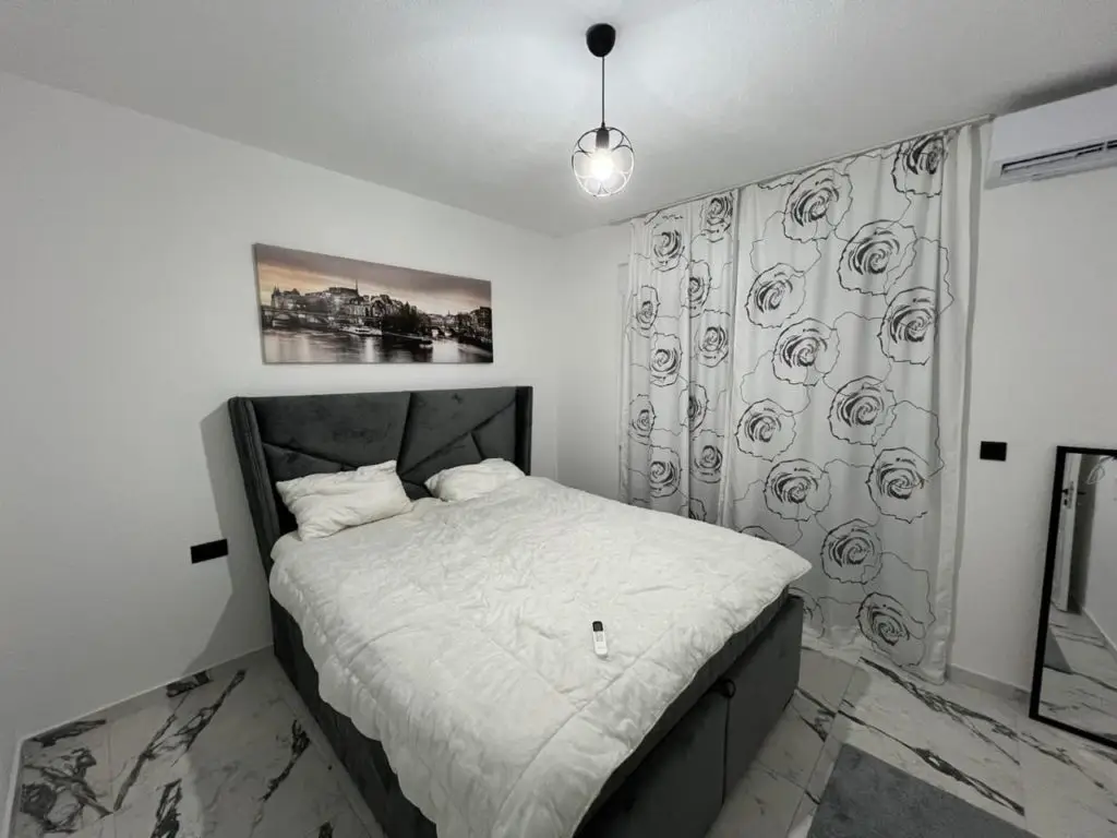 Modern bedroom with double bed, floral curtains, and wall art