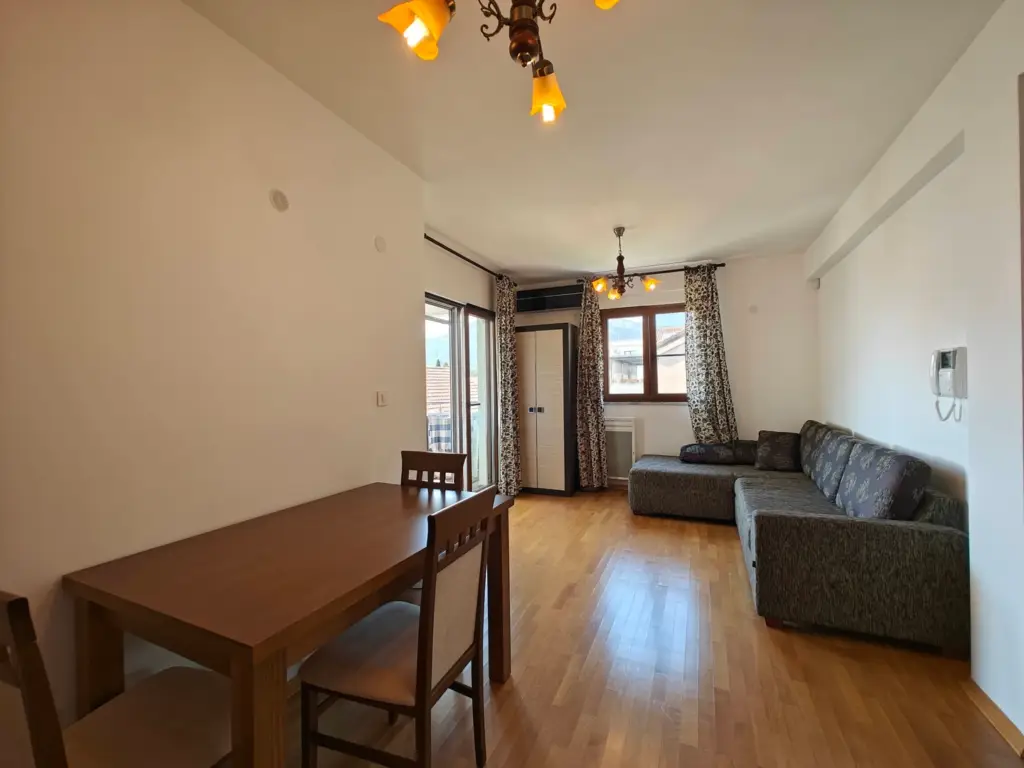 Living room with dining table, gray sofa, and balcony doors