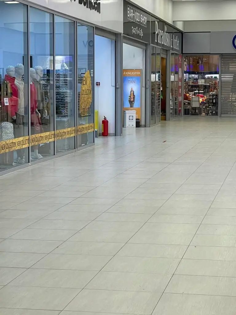 Shopping mall corridor with storefronts and mannequins behind glass