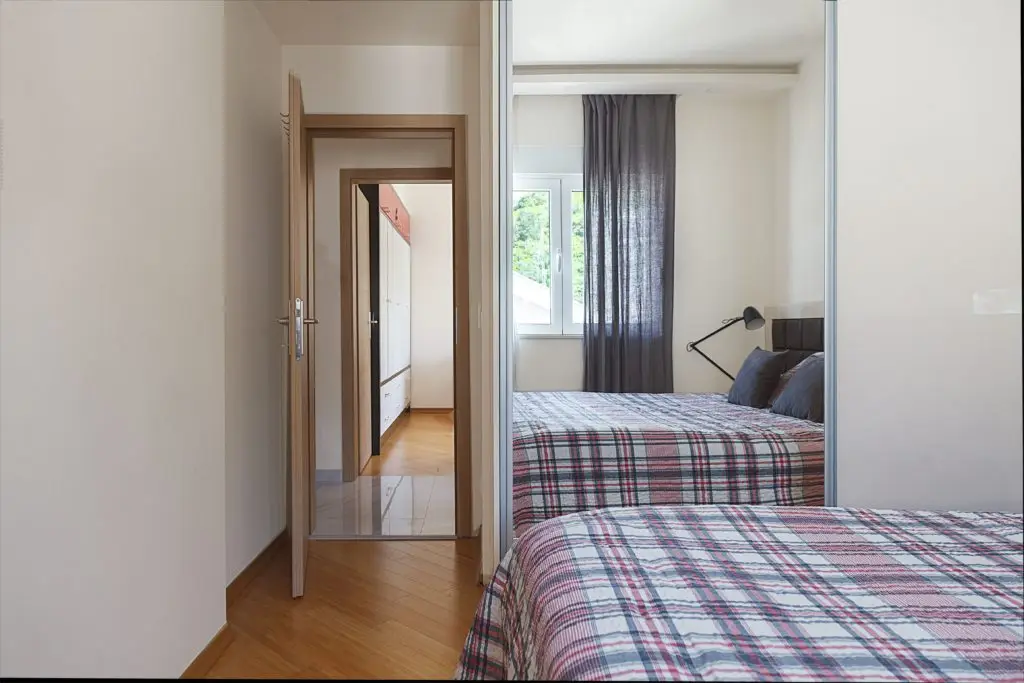 Bedroom with plaid beds and mirrored wardrobe door