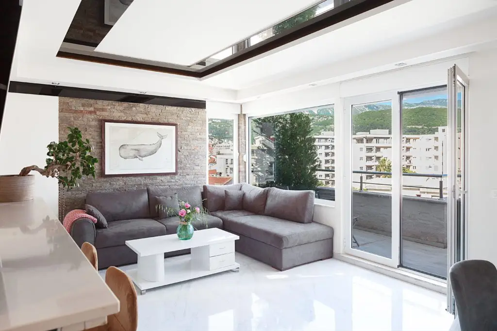 Bright living room with gray sectional, coffee table, and balcony view