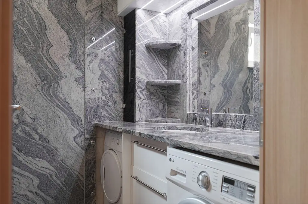 Marble-clad bathroom with sink, mirror, and LG washer-dryer