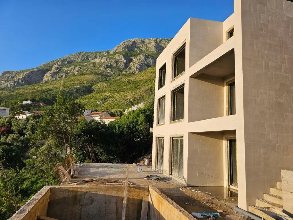 Beige apartment building under construction with mountain backdrop