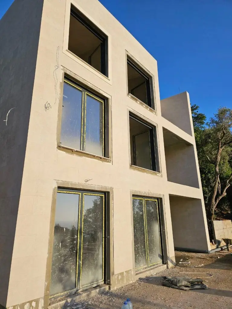 Unfinished beige apartment building with large windows under blue sky