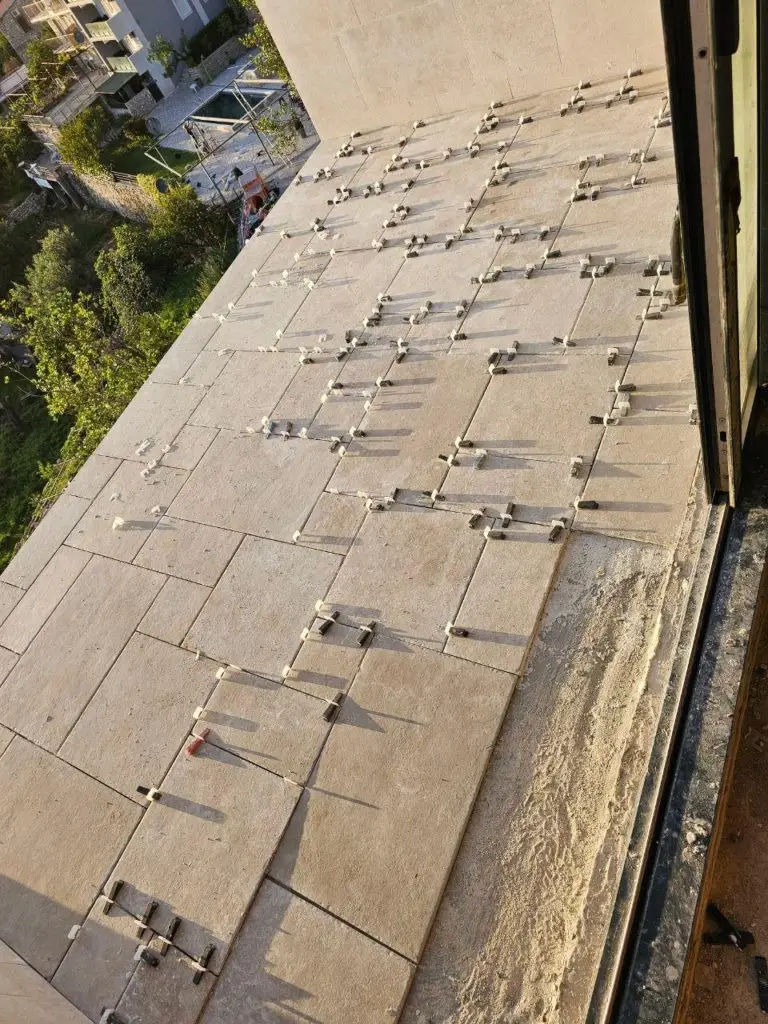 Beige balcony tiles with leveling clips near doorway