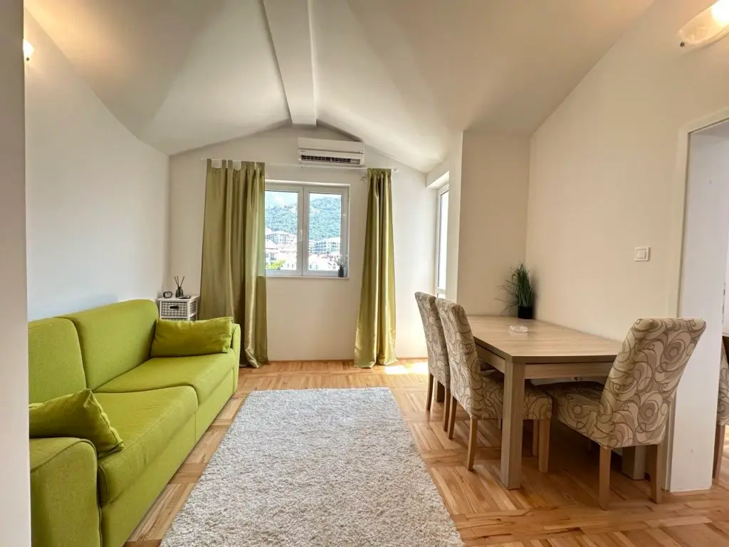 Living-dining room with green sofa, table, and chairs