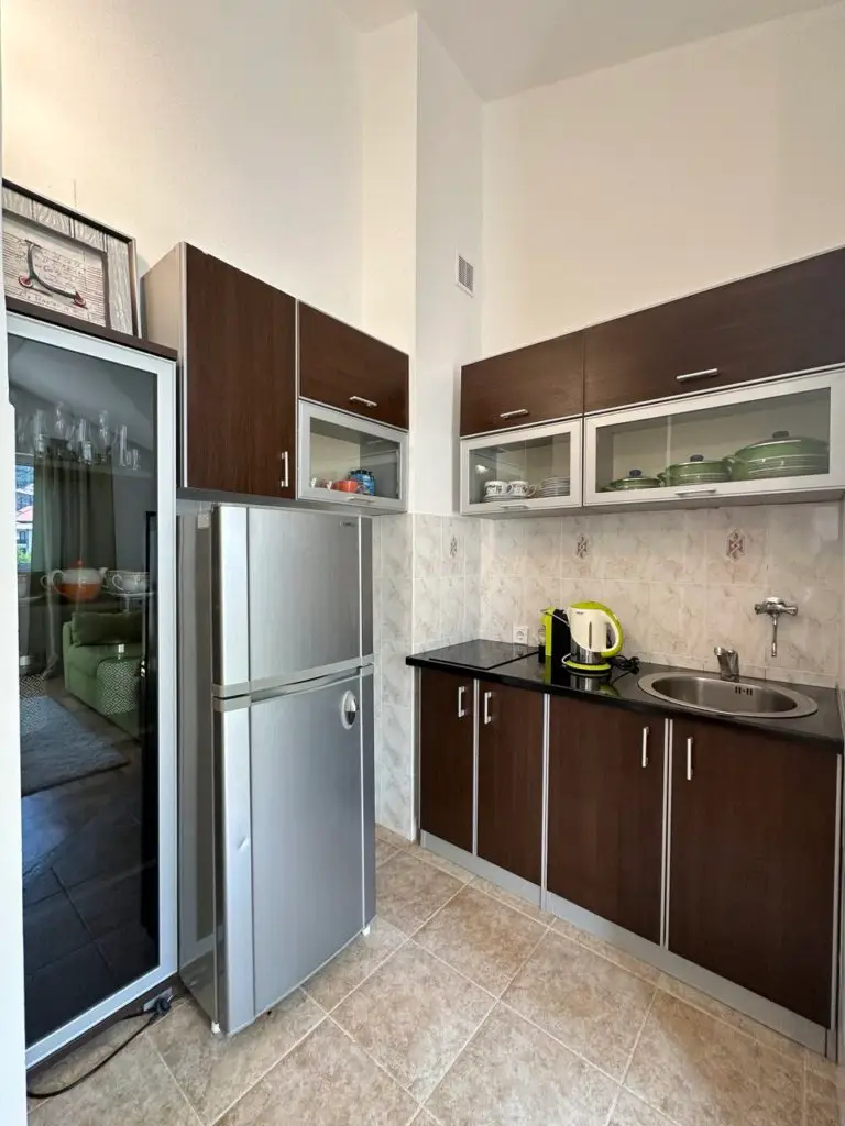 Compact kitchen with silver fridge, dark cabinets, and sink