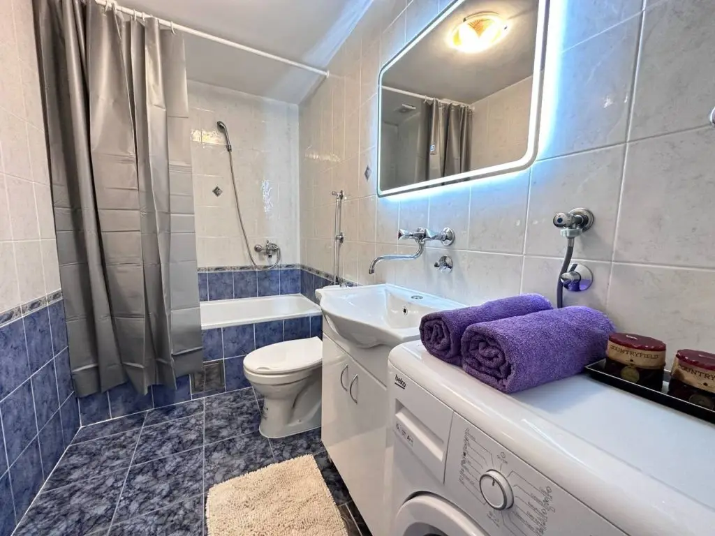 Small bathroom with bathtub, toilet, sink, and washing machine