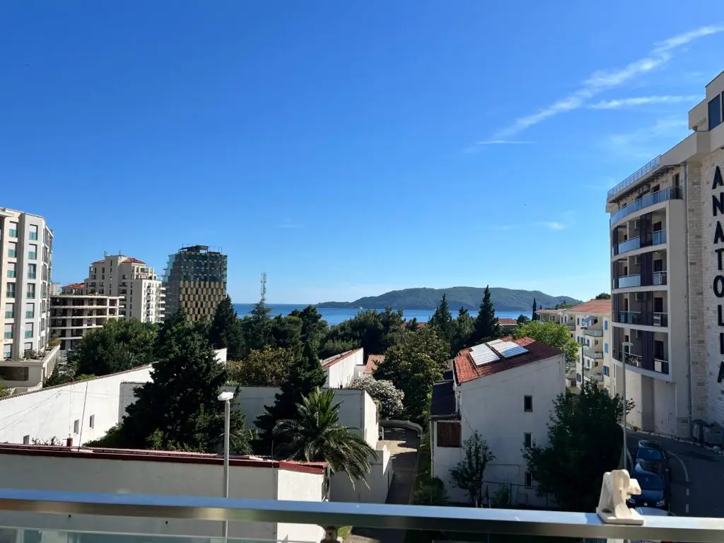Balcony view over buildings, sea, and distant island
