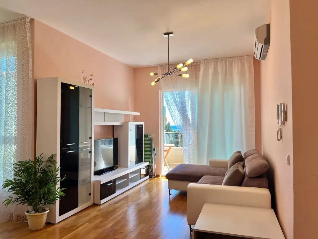 Living room with brown sectional, TV unit, and balcony door