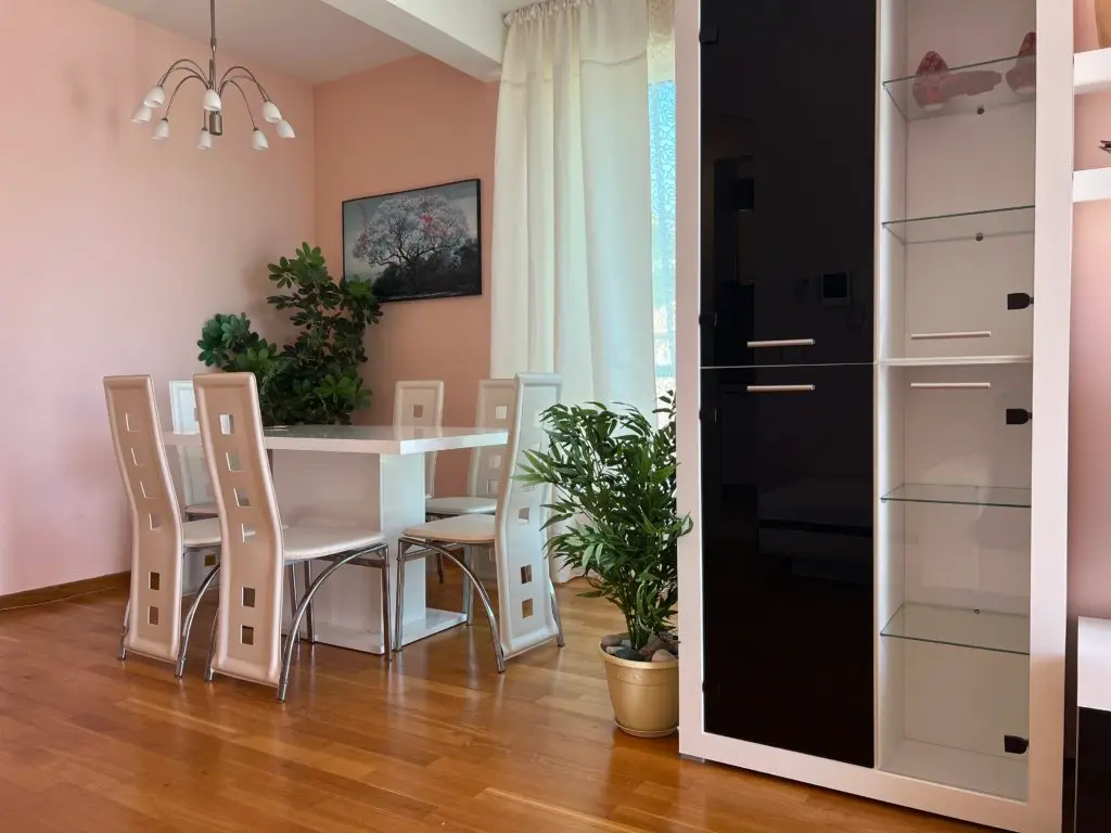 Dining area with white table, beige chairs, and plants