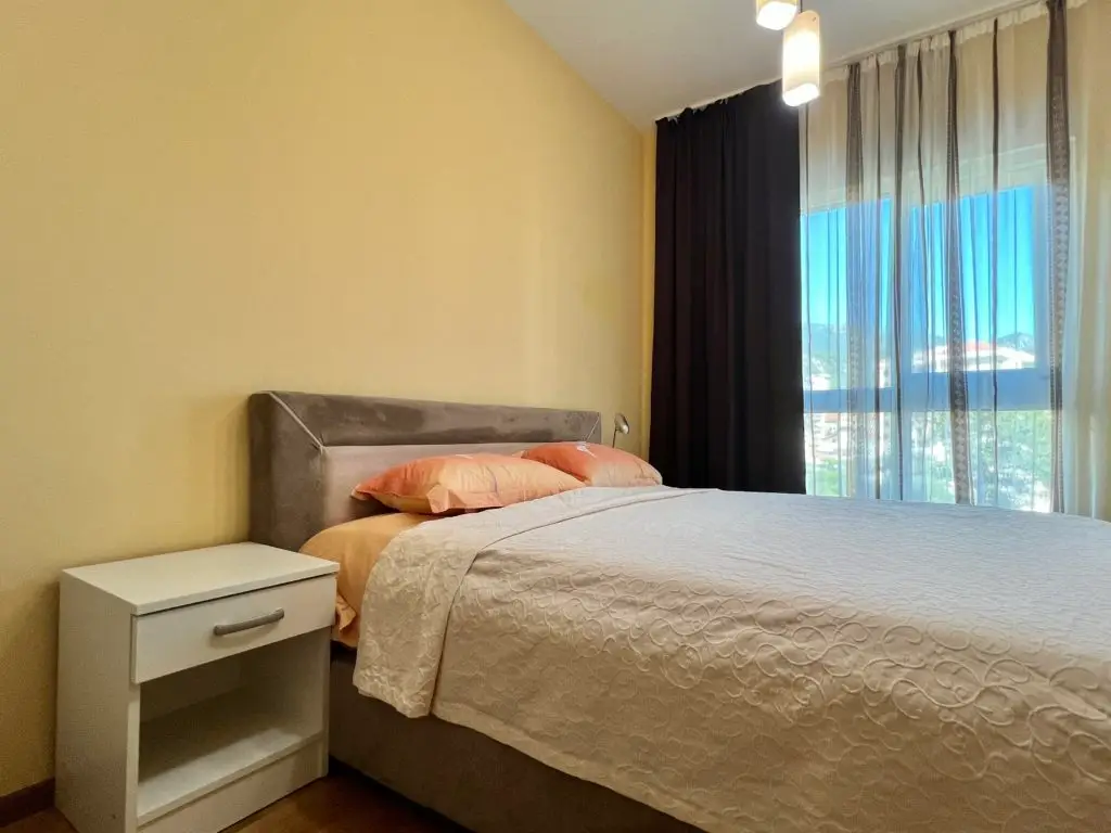 Bedroom with double bed, nightstand, and window curtains