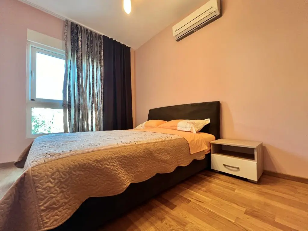 Bedroom with double bed, nightstand, window, and wall-mounted air conditioner