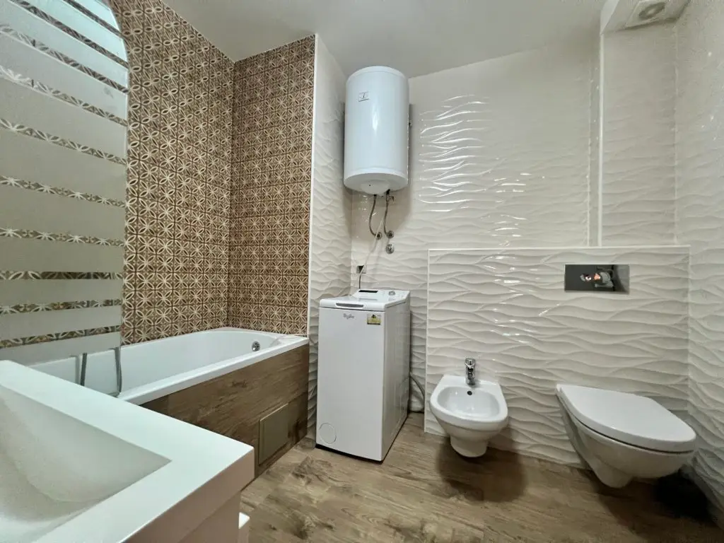 Modern bathroom with bathtub, washing machine, bidet, and toilet