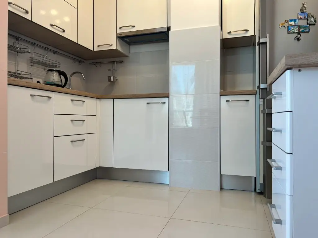White kitchen cabinets with wood countertop and kettle