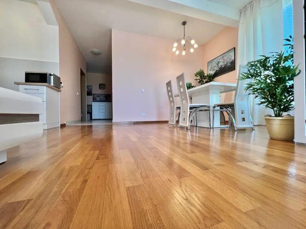 Living room with wooden floor, white dining table, and potted plants
