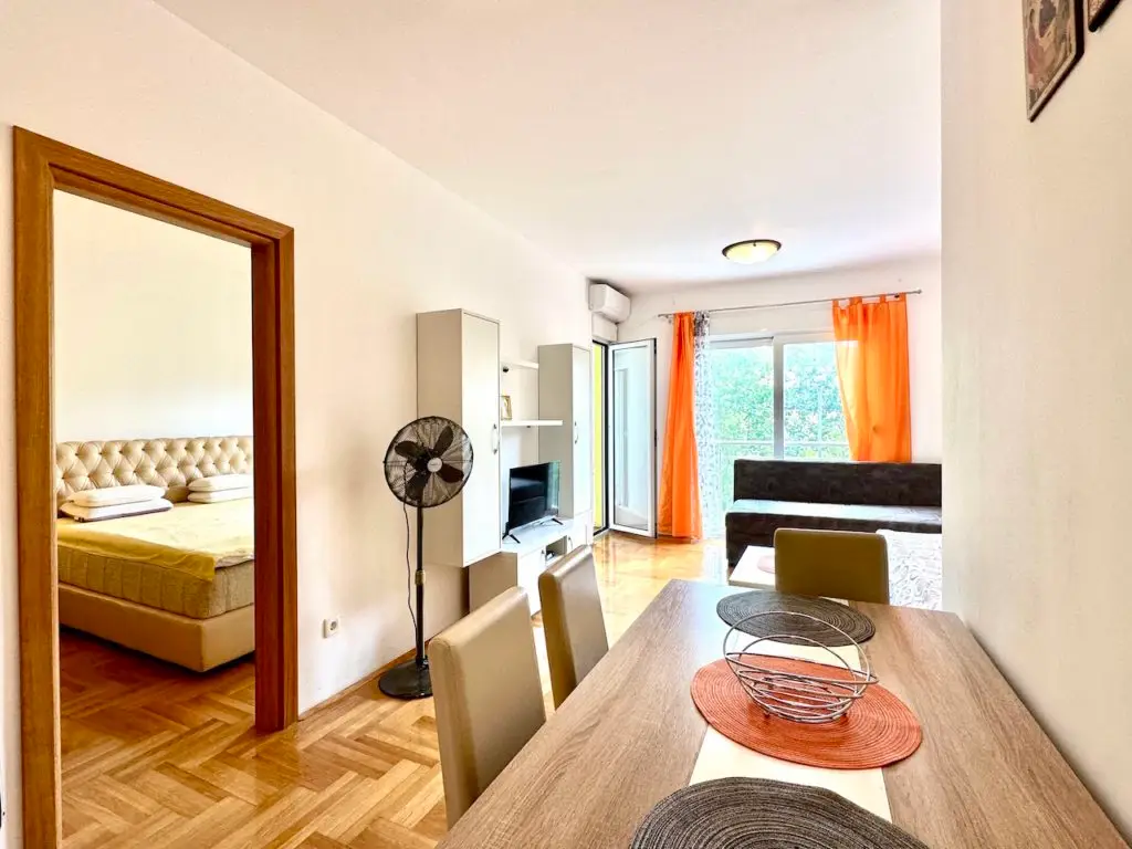 Bright apartment interior with dining table, sofa, and bedroom doorway