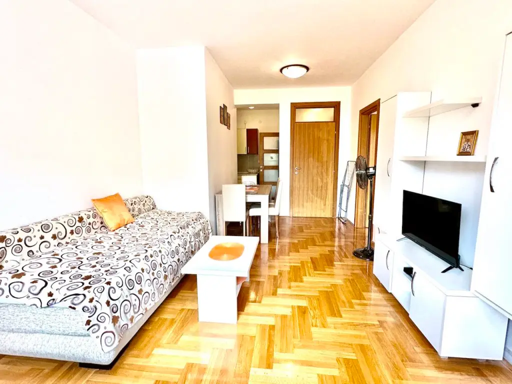Small living room with sofa, TV, dining table, and fan