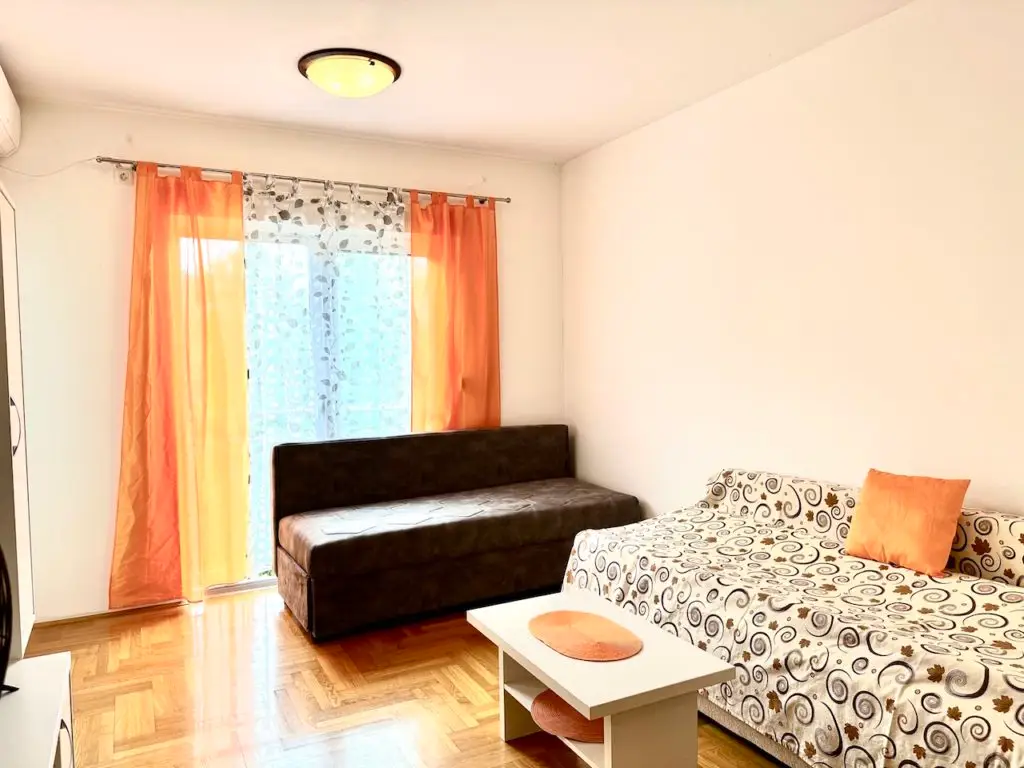 Small living room with two sofas, coffee table, and orange curtains