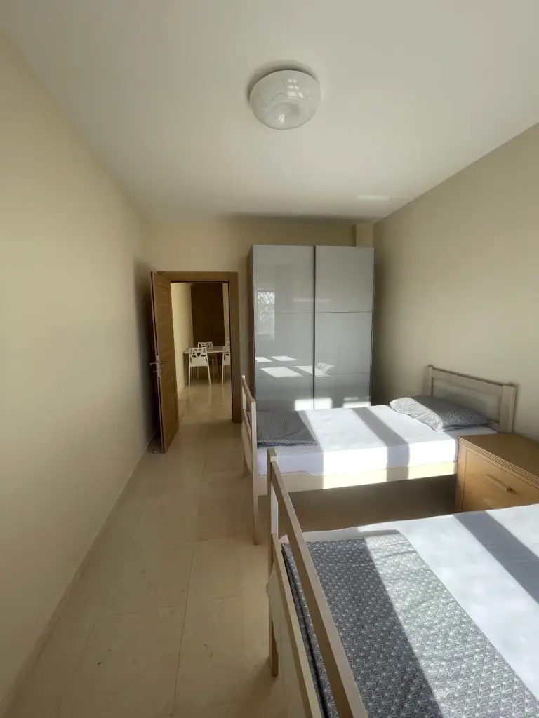 Bedroom with two single beds, wardrobe, and open door to dining area