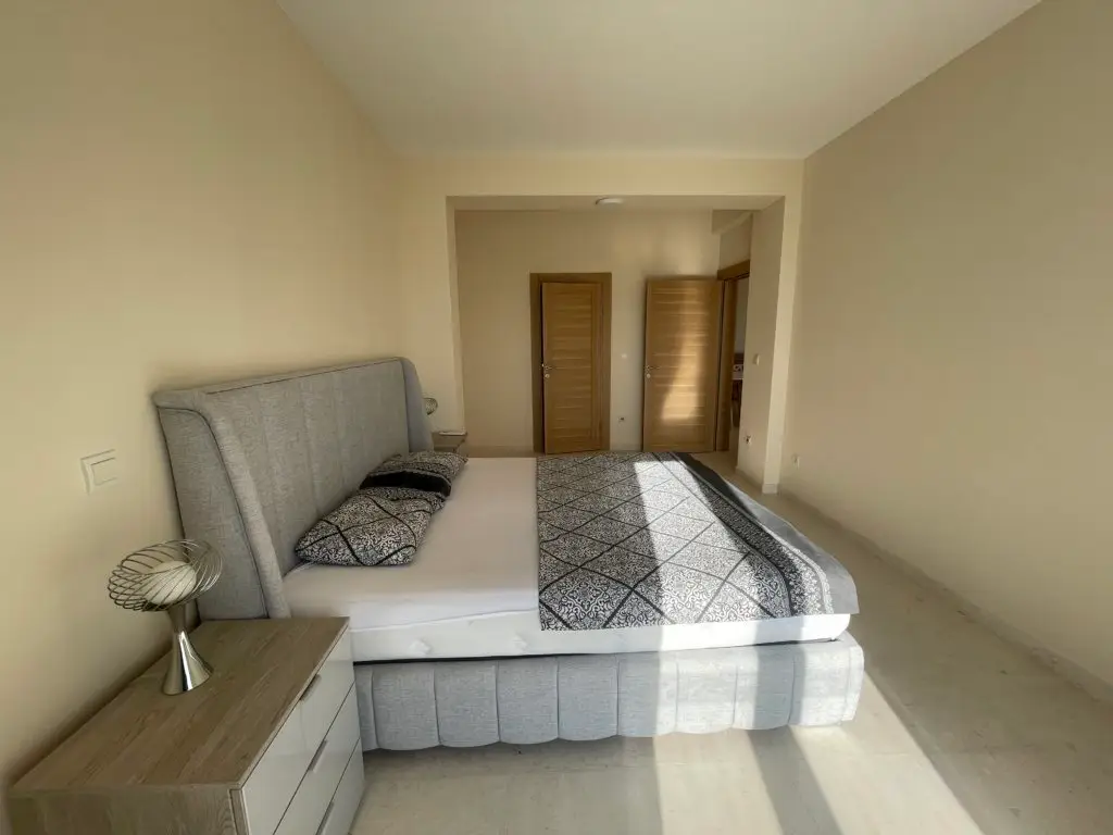 Bedroom with gray bed, bedside table, and two wooden doors
