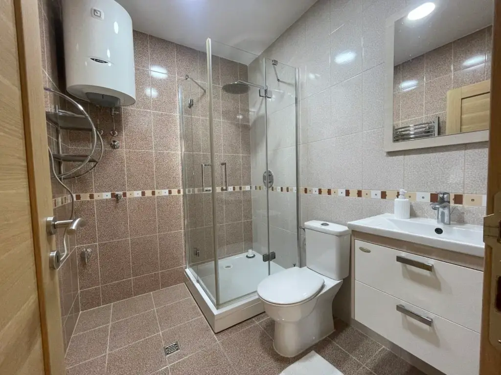 Modern bathroom with shower enclosure, toilet, sink, and mirror