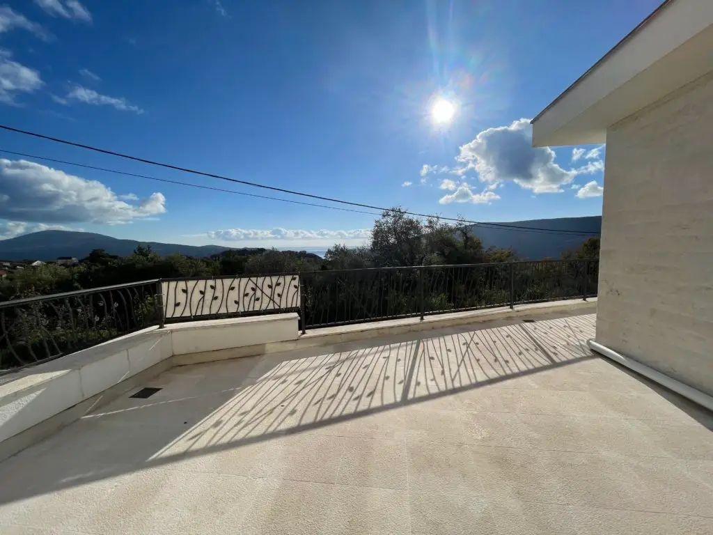 Sunny terrace with mountain and sea view, black railing shadows
