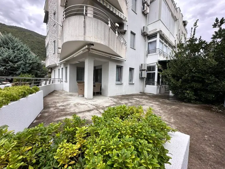 White apartment building with balcony and courtyard plants