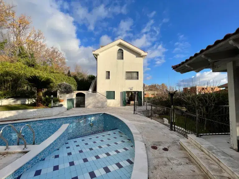 Villa with empty tiled swimming pool and patio