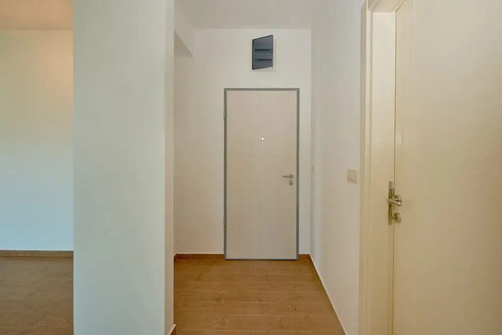 Apartment hallway with white doors and wooden floor