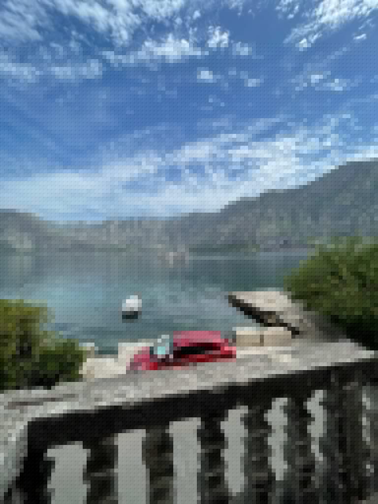 Mountain bay with boats, dock, and red car in foreground