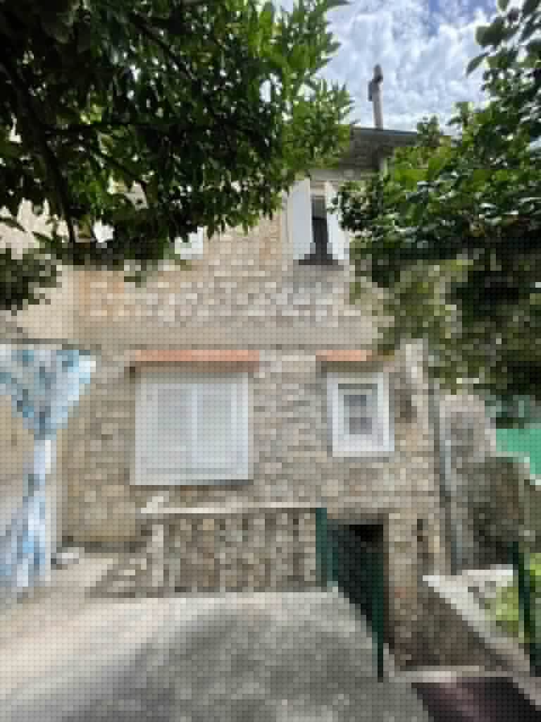 Stone house exterior with white shutters and leafy trees