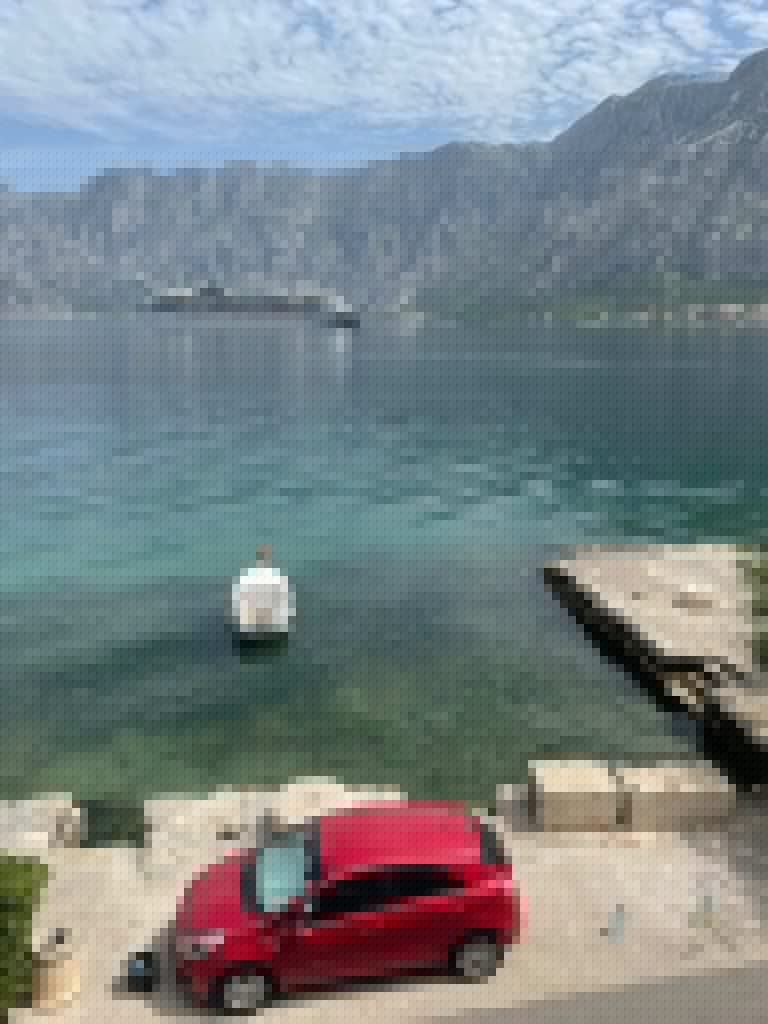 Bay with cruise ship, small boat, and red car in foreground