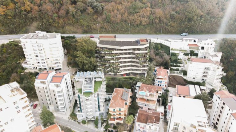 Aerial view of apartment buildings beside a wooded hillside