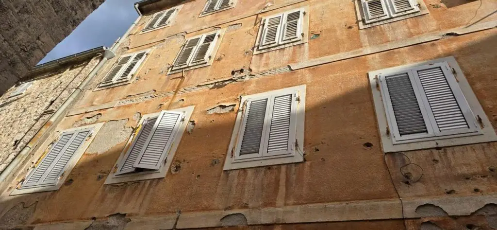 Low-angle view of an orange facade with white shutters
