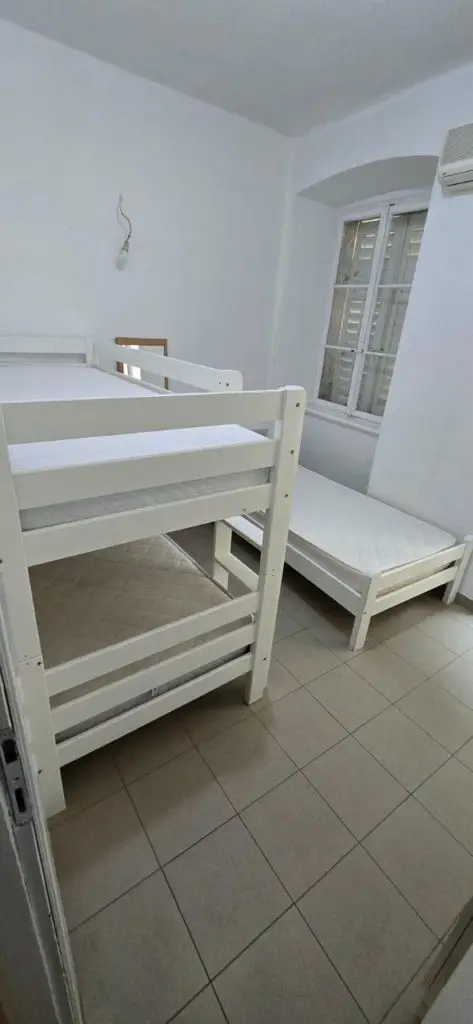 Small white bedroom with bunk bed, single bed, and window