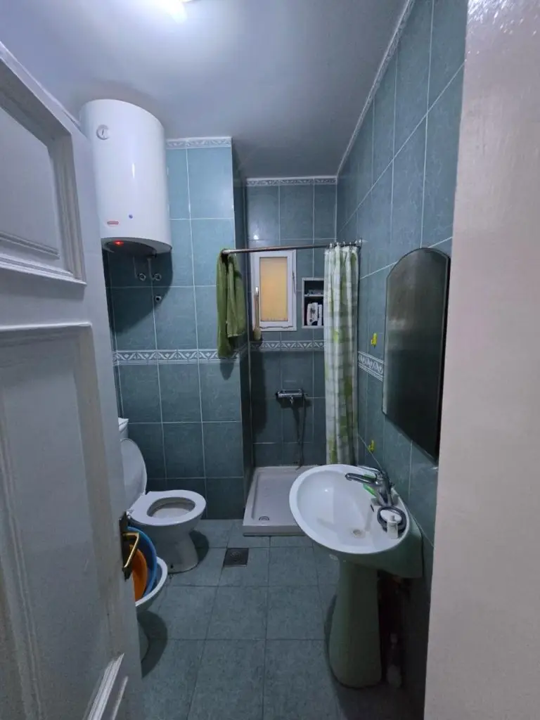 Small tiled bathroom with shower, sink, toilet, and water heater
