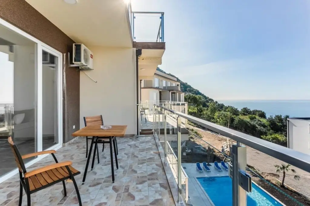Balcony with table, chairs, sea view, and pool below