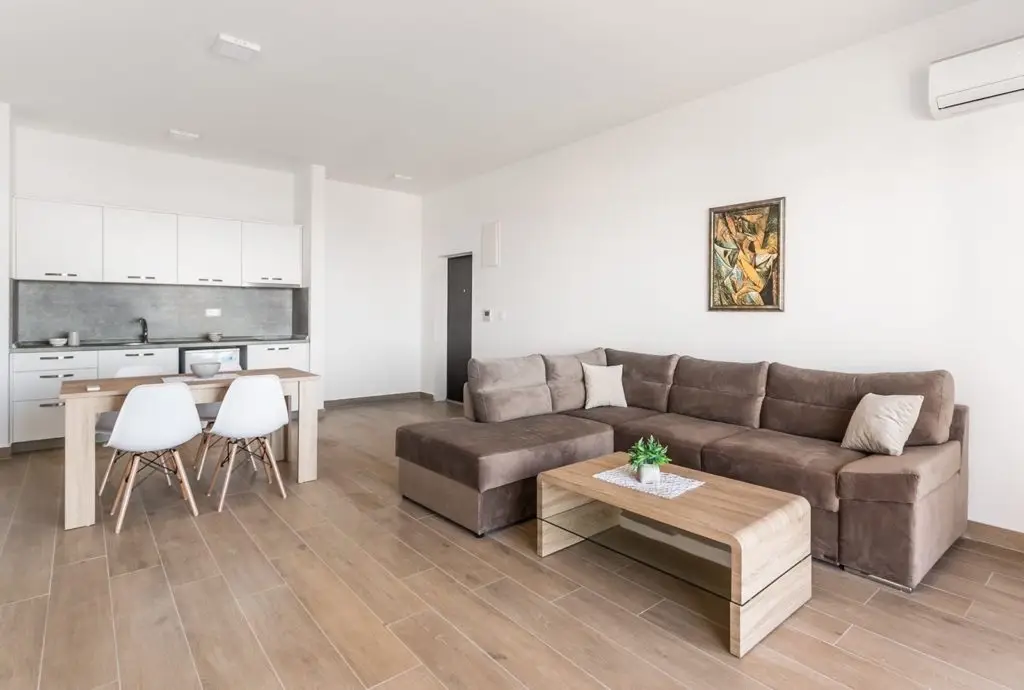 Open-plan living room with kitchen, brown sectional sofa, and dining table